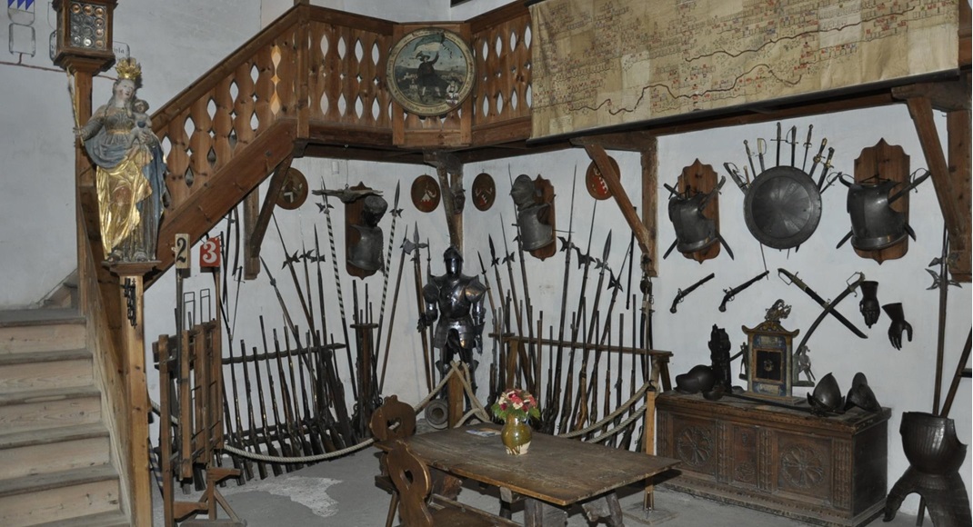 Room with armor, halberds, shields, and wooden stairs