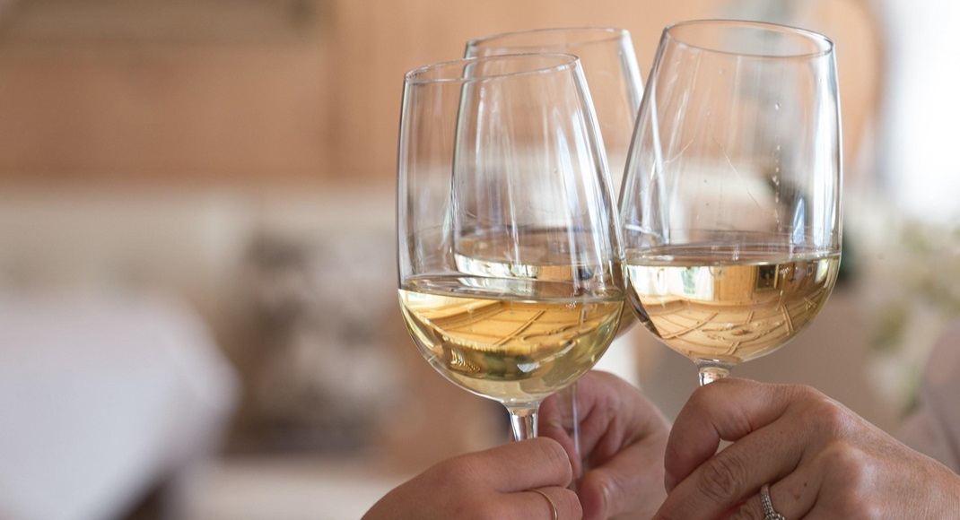 Tre persone fanno un brindisi con vino bianco
