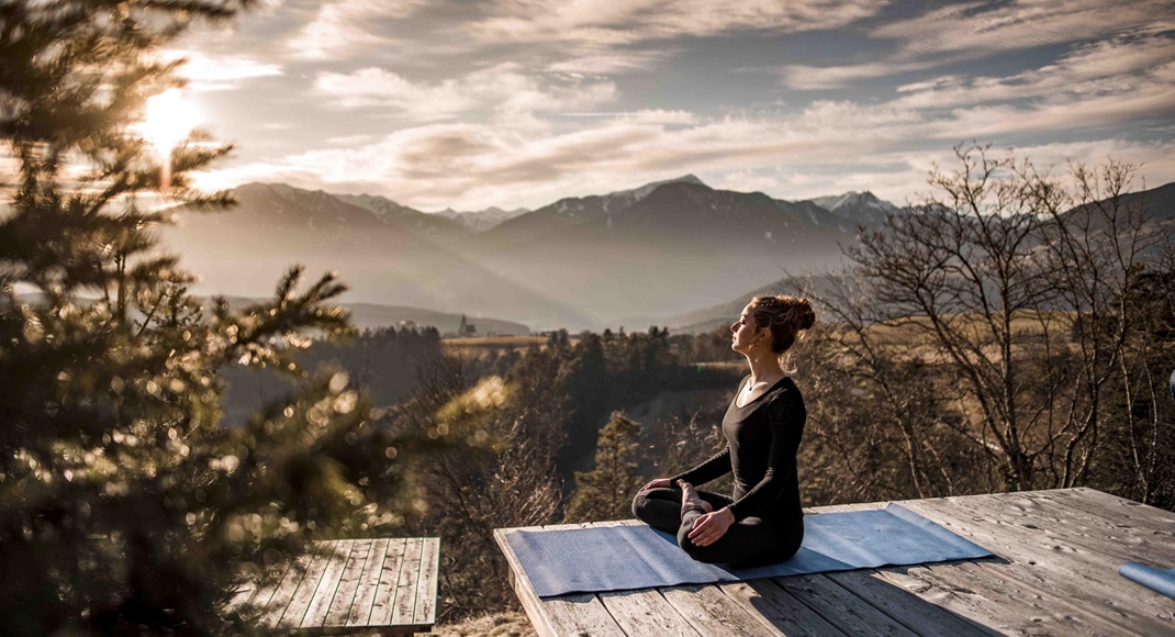 A woman is doing outdoor yoga at sunrise