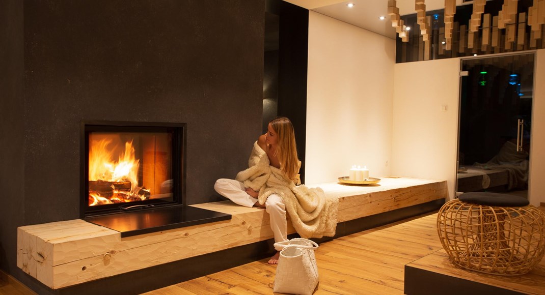 A woman in a relaxation area with a lit fireplace