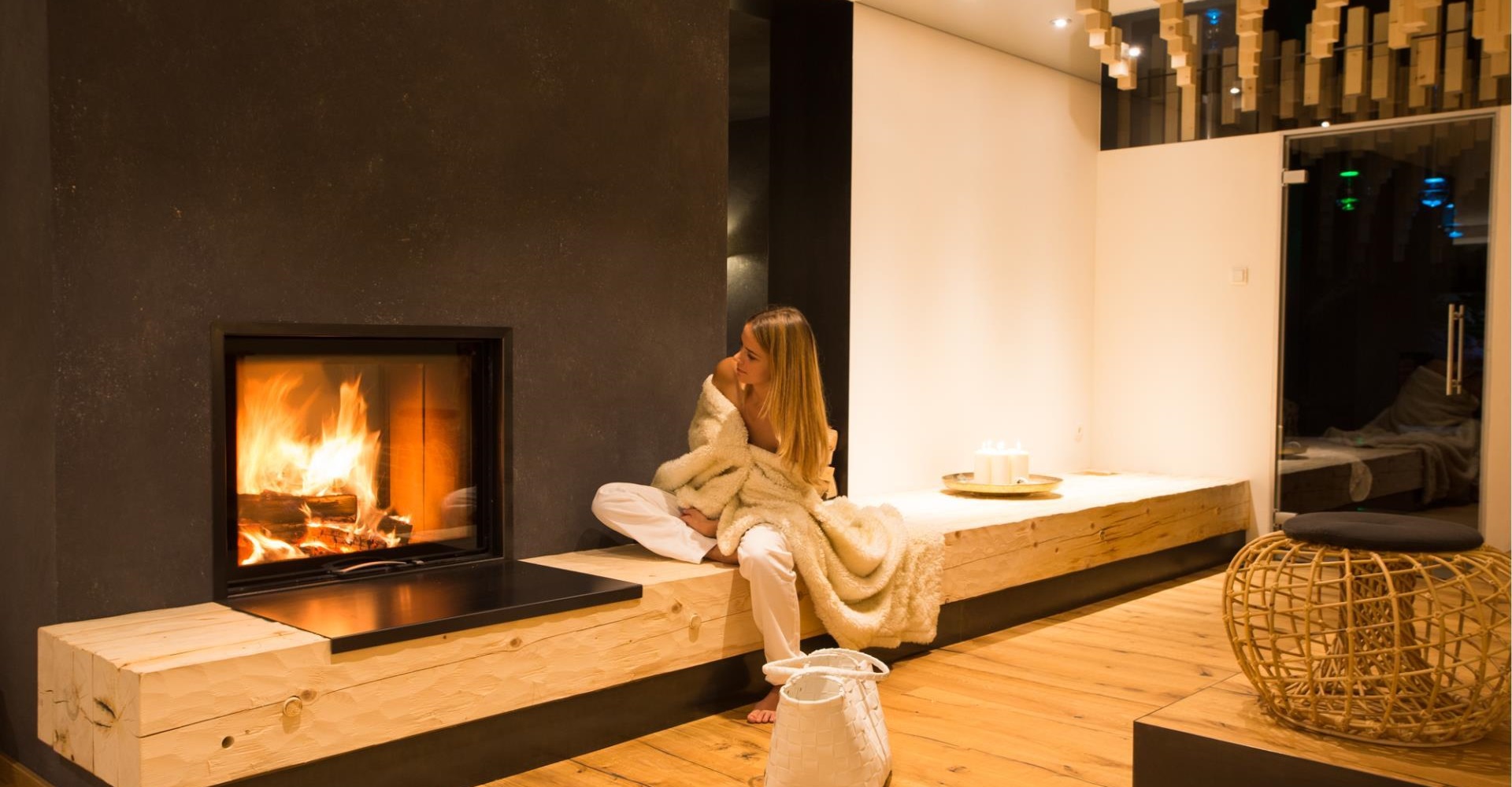 A woman in a relaxation area with a lit fireplace