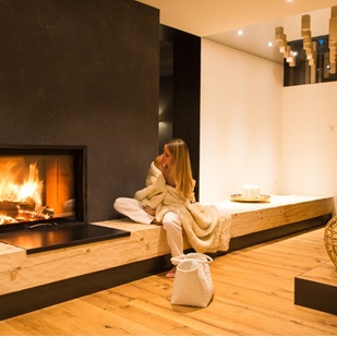 A woman in a relaxation area with a lit fireplace