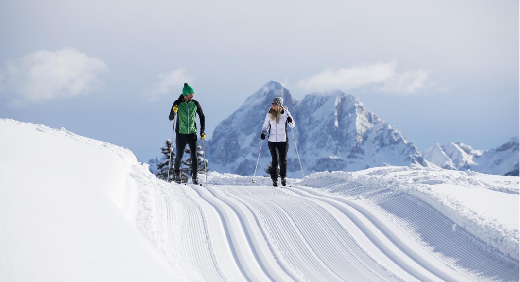 A man and a woman are cross-country skiing