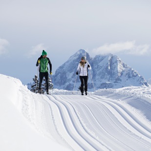 A man and a woman are cross-country skiing