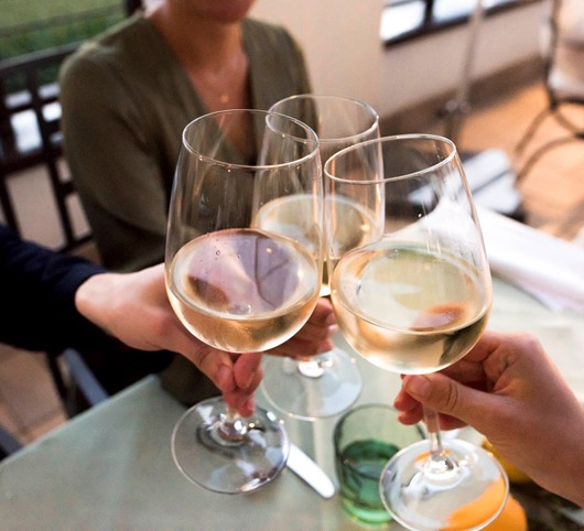 Drei Personen stoßen mit Weißwein an