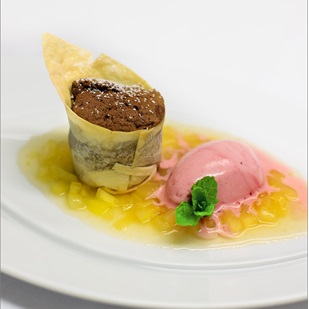 Tortino al cioccolato con salsa di frutta, gelato rosa e menta
