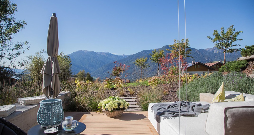 Moderne Terrasse mit Lounge und Bergblick an einem sonnigen Herbsttag.