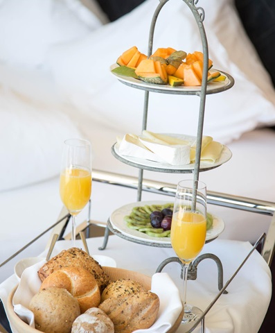 Colazione con pane, formaggio, frutta e succo d’arancia