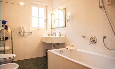 Das Badezimmer mit Waschbecken, WC und Badewanne