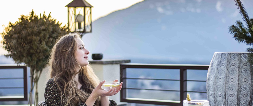 A woman is having a cup of tea on the terrace