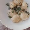 Hausgemachte Gnocchi mit Schaum, Parmesan und frischen Kräutern auf einem weißen Teller.