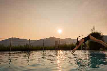 A woman is jumping into the outdoor pool at sunrise