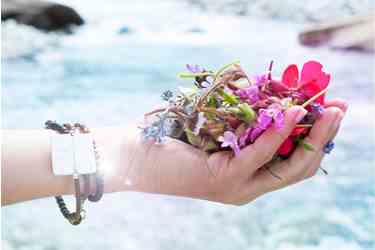 Hand hält bunte Wildblumen vor fließendem Wasser